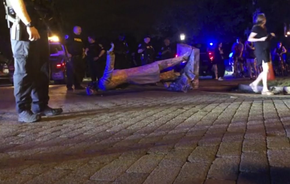 In this image from video, police stand near a toppled statue of Jefferson Davis on Wednesday night, June 10, 2020, in Richmond, Va. Protesters tore down the statue of Confederate President Davis along Monument Avenue. The statue in the former capital of the Confederacy was toppled shortly before 11 p.m., news outlets reported. 