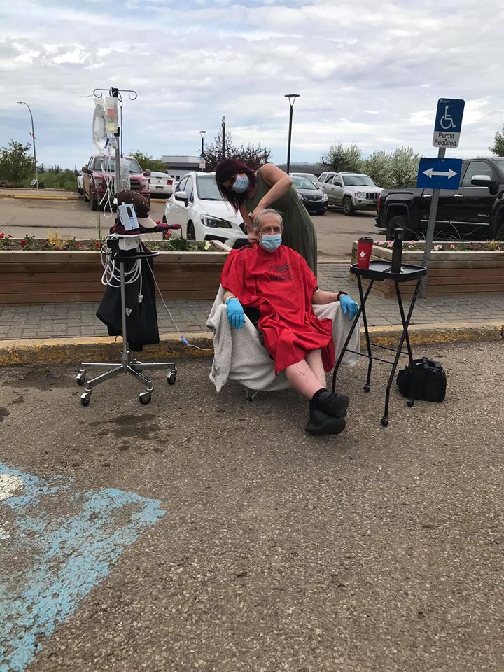 Lacey Mitchell cuts Paul Walsh's hair in the parking lot of the Northern Lights Regional Health Centre in Fort McMurray, Alta.