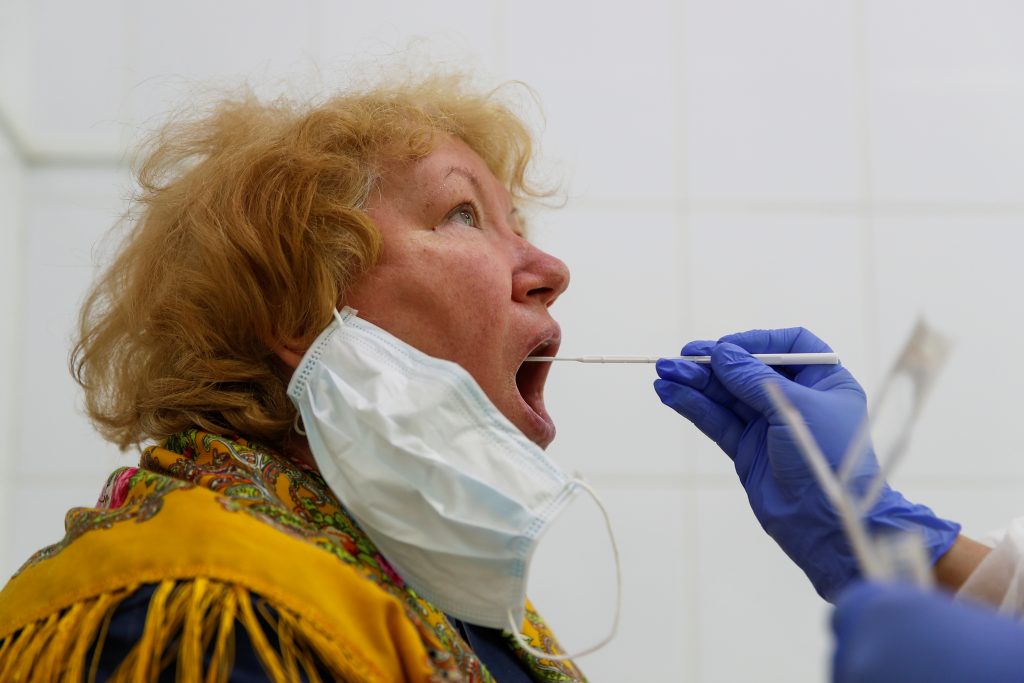 A healthcare worker takes a swab from a woman during testing for the coronavirus disease (COVID-19) and antibodies at a clinic after authorities launched free mass screening for residents in the Russian capital, in Moscow, Russia May 15, 2020.
