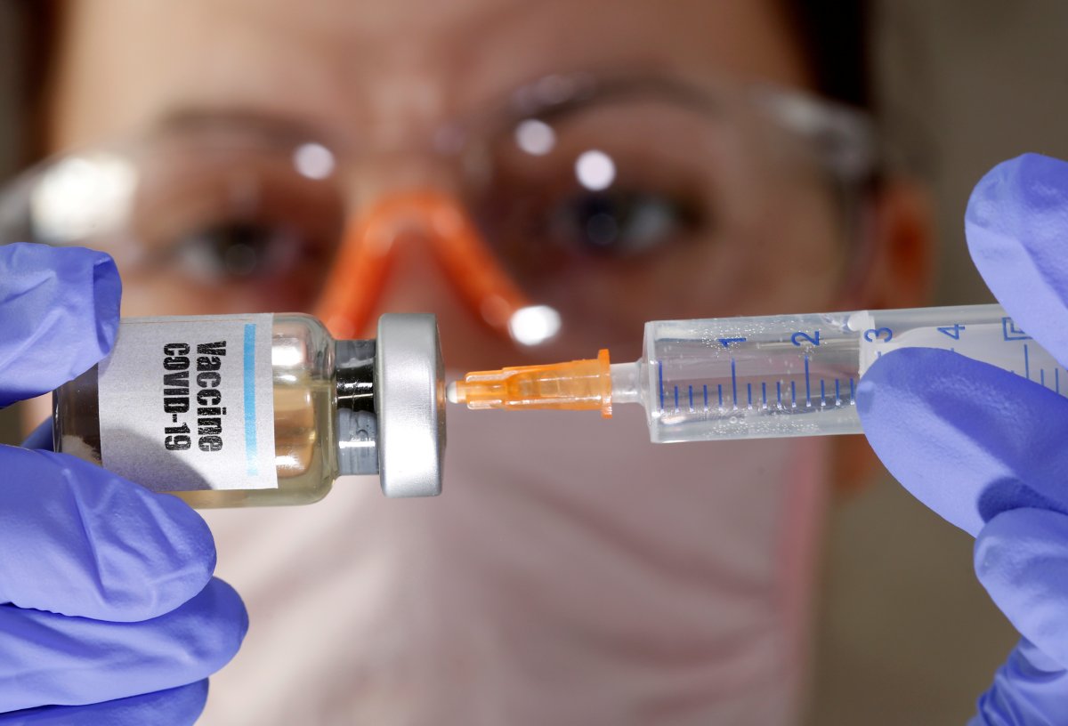 FILE PHOTO: A woman holds a small bottle labeled with a "Vaccine COVID-19" sticker and a medical syringe in this illustration taken April 10, 2020. REUTERS/Dado Ruvic/Illustration/File Photo.