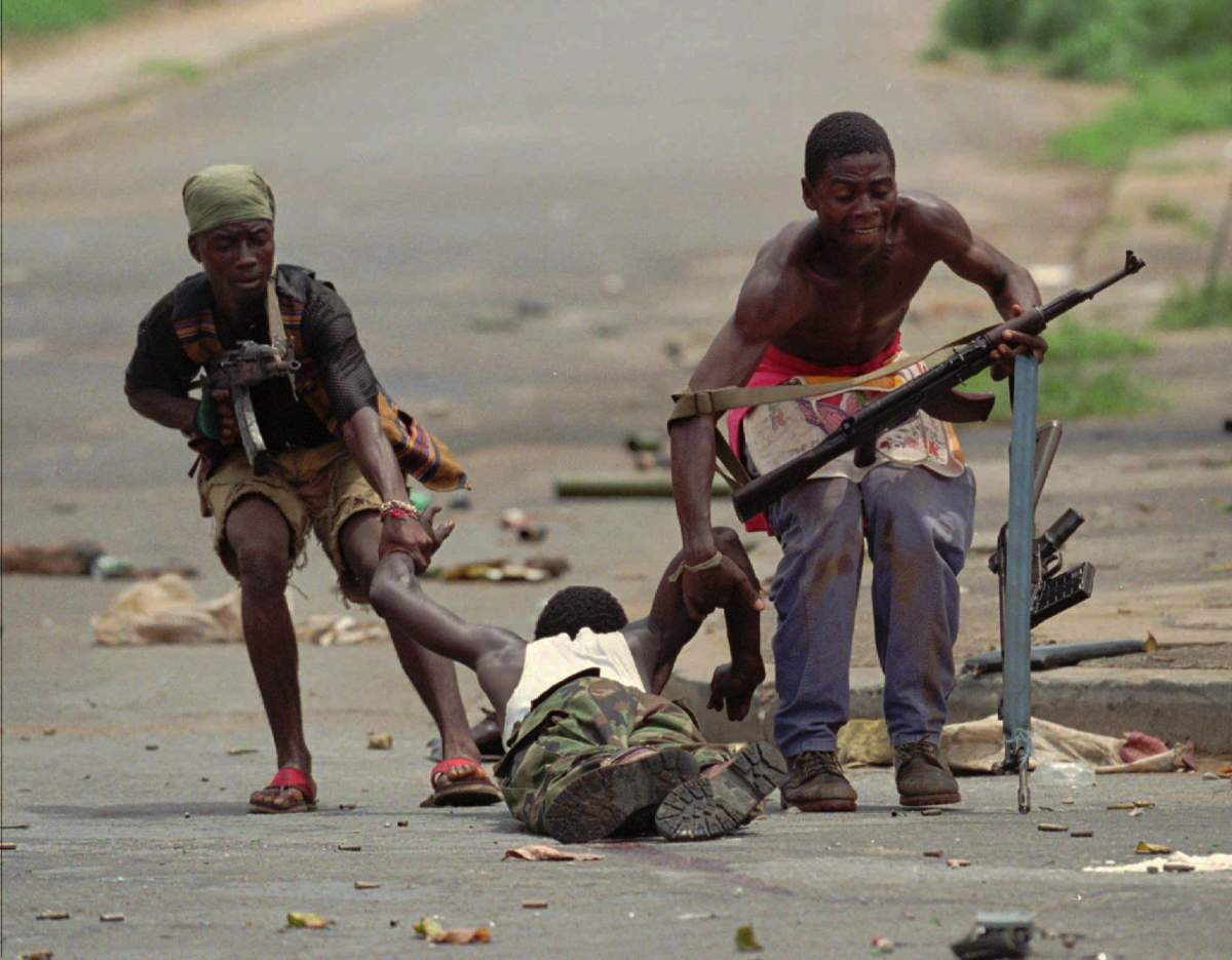 National Patriotic Front of Liberia (NPFL) fighters drag a wounded man out of a front-line street in Monrovia, Liberia Tuesday, April 16, 1996.