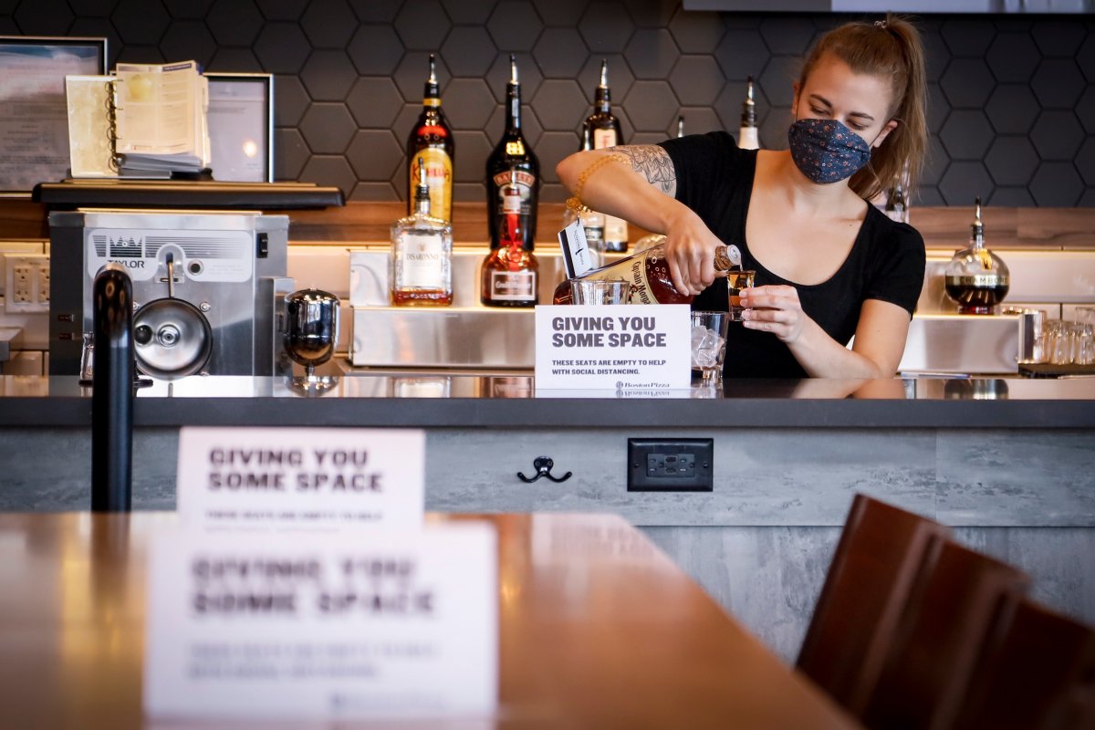 A bartender pours a drink at a Boston Pizza after its reopening in Airdrie, Alta., Thursday, May 14, 2020, amid a worldwide COVID-19 pandemic. 