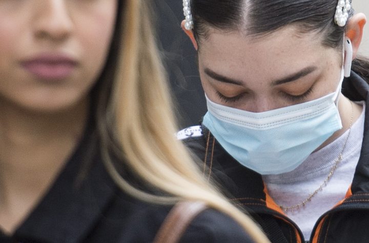 FILE - A woman wears a face mask and another does not as they wait in line outside a store on Sainte-Catherine street in Montreal, Sunday, May 31, 2020, as the COVID-19 pandemic continues in Canada and around the world.