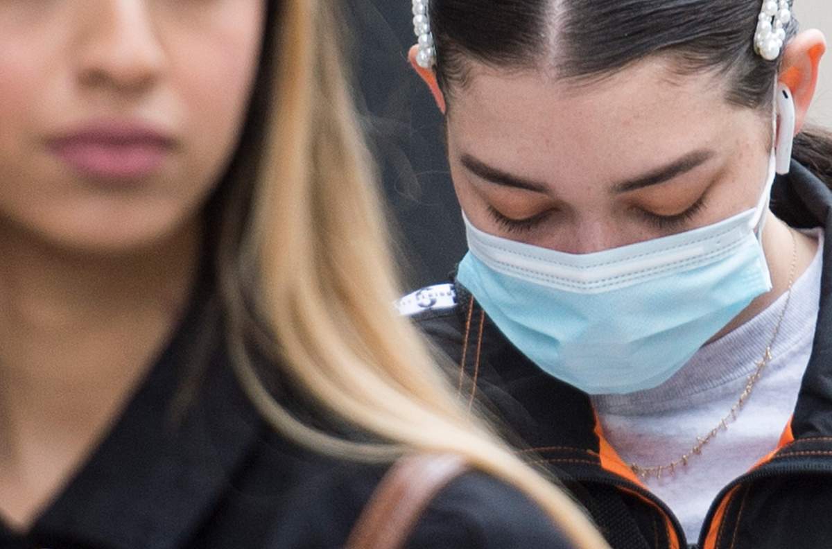 A woman wears a face mask and another does not as they wait in line outside a store on Sainte-Catherine Street in Montreal, Sunday, May 31, 2020.