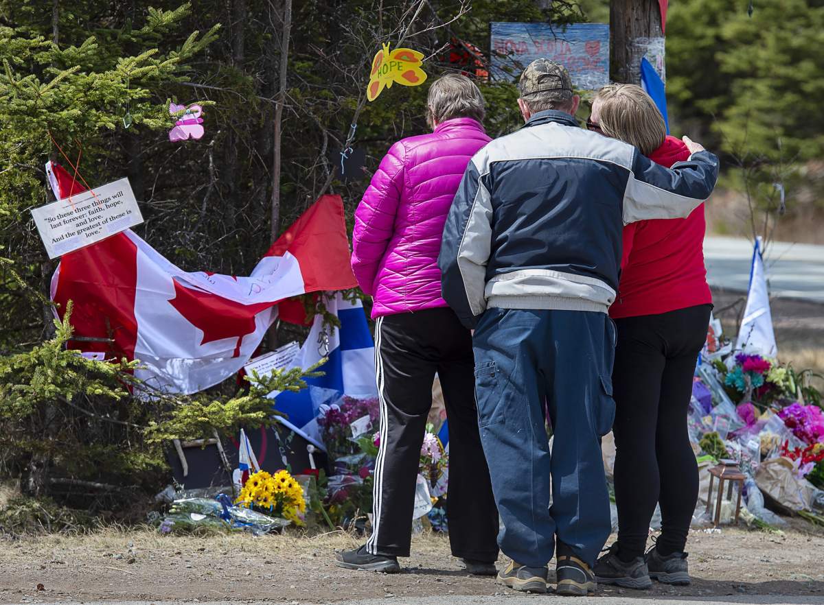 A family pays their respects to victims of the mass killings at a checkpoint on Portapique Road in Portapique, N.S. on Friday, April 24, 2020.