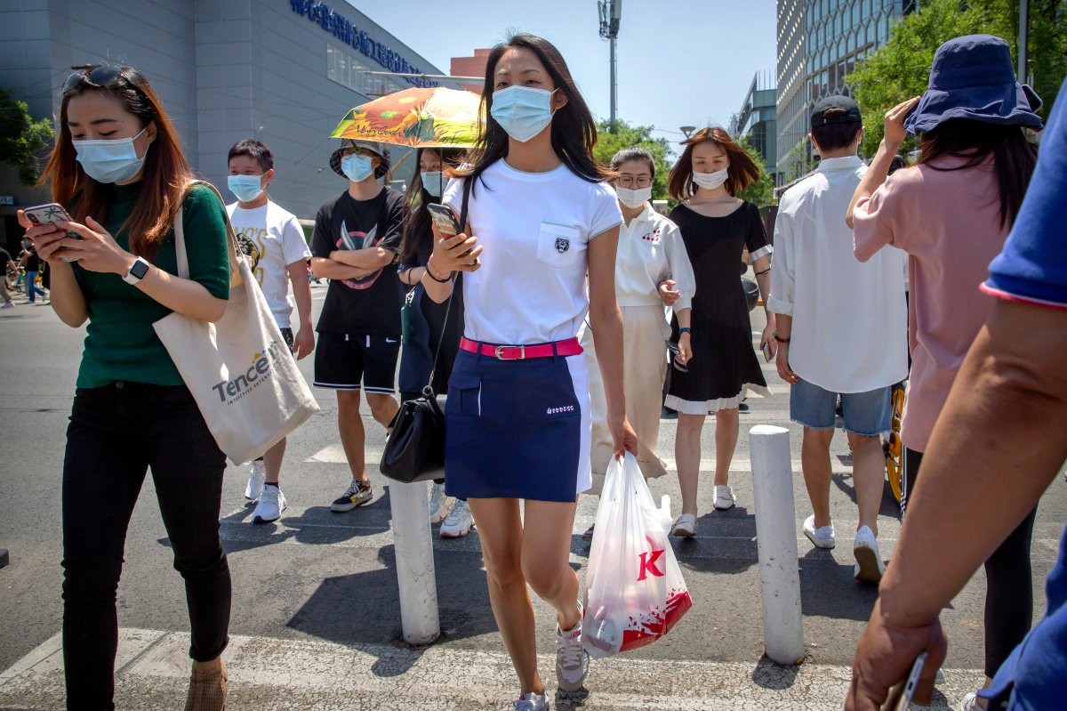 People wear face masks to protect against the coronavirus as they walk across an intersection in Beijing, Friday, June 5, 2020.