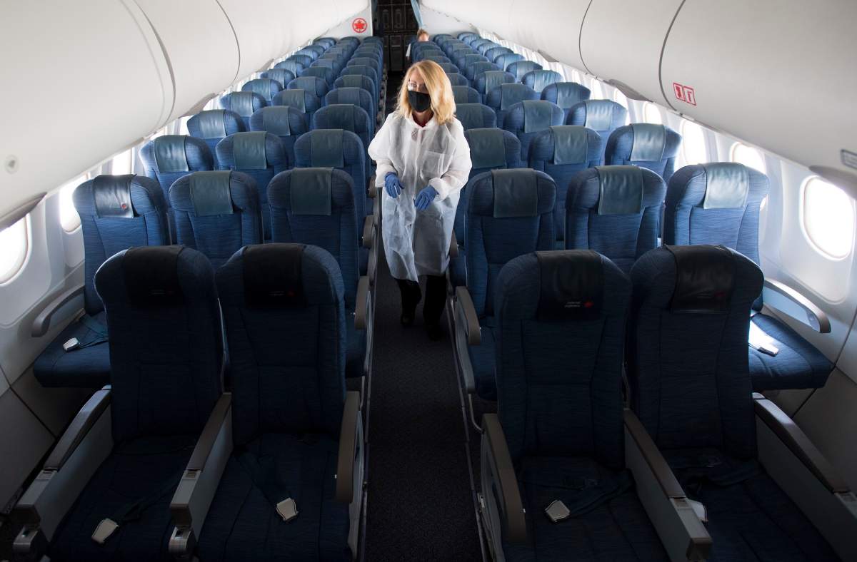 A flight attendant wears personal protective equipment as they walk through the back part of a near empty plane travelling from Calgary to Vancouver, Tuesday, June 9, 2020.