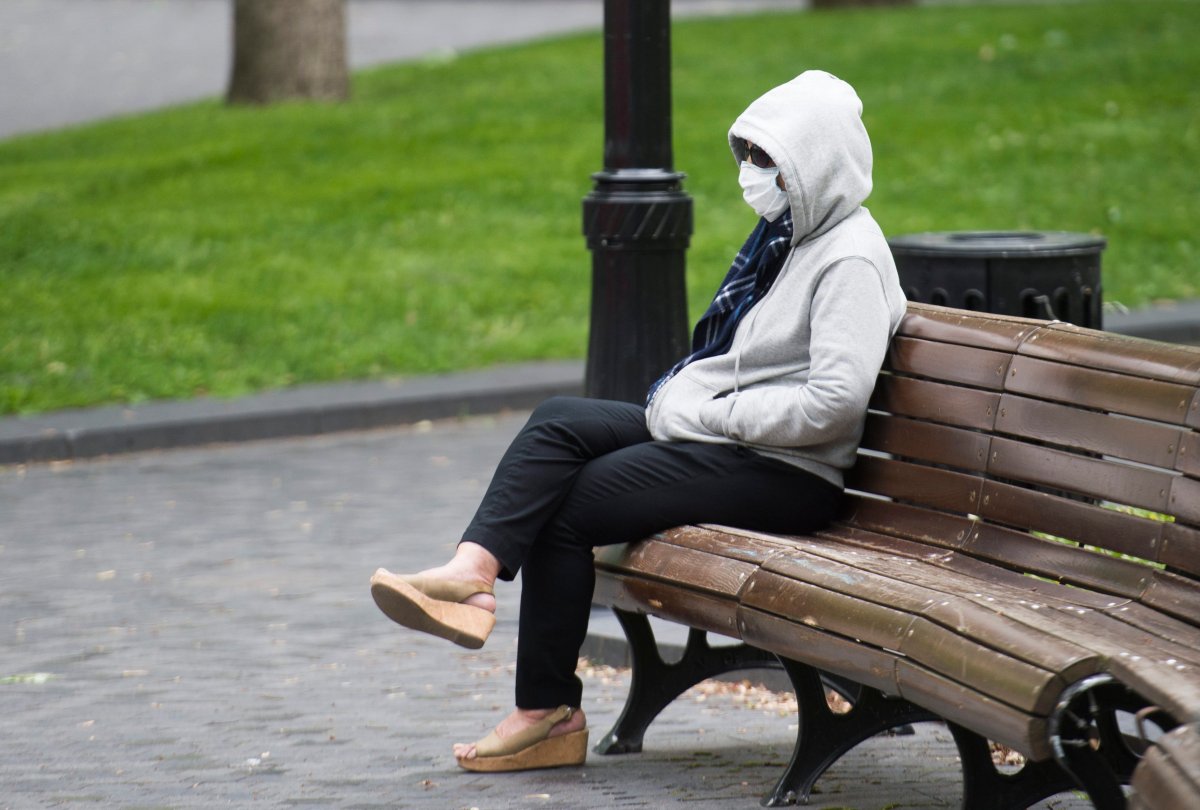 A person wears a face mask while sitting in a city park in Montreal, Sunday, May 31, 2020, as the COVID-19 pandemic continues in Canada and around the world. THE CANADIAN PRESS IMAGES/Graham Hughes.