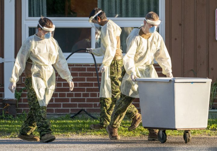 Members of the Canadian Forces assisting with COVID-19 care wash down a laundry bin in the parking lot of Altamont Care Community in Toronto on Monday, June 15, 2020.