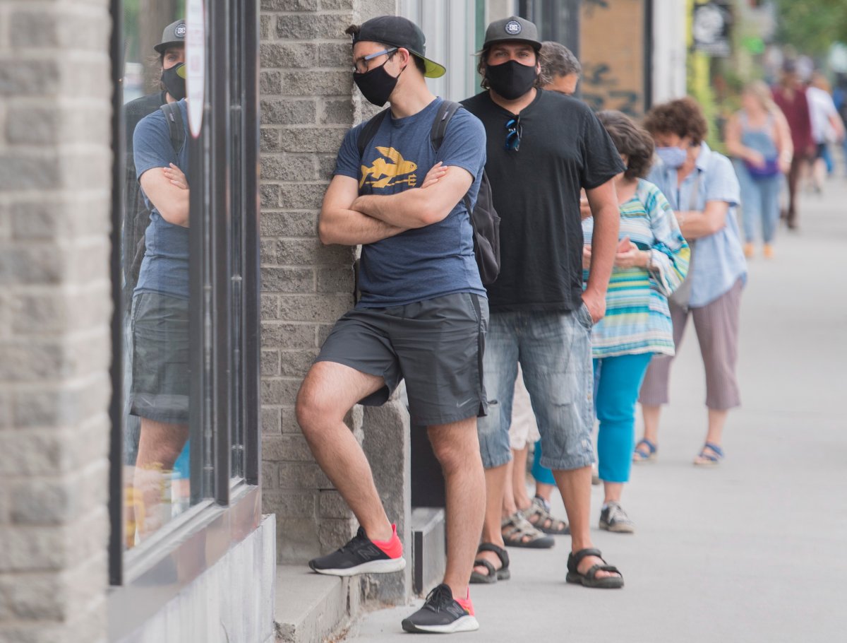 People wear face masks as they wait to enter a store in Montreal, Saturday, June 27, 2020, as the COVID-19 pandemic continues in Canada and around the world. 