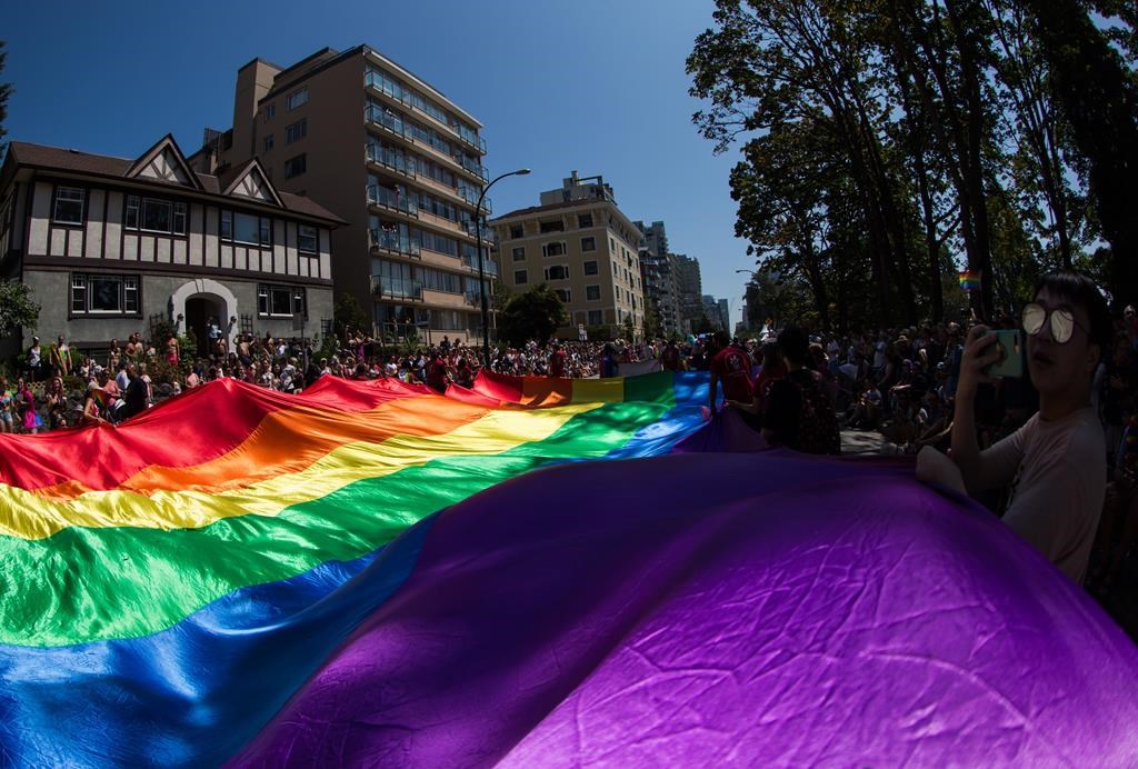 A large rainbow flag is carried by people marching in the Vancouver Pride Parade, in Vancouver, Sunday, Aug. 4, 2019. 