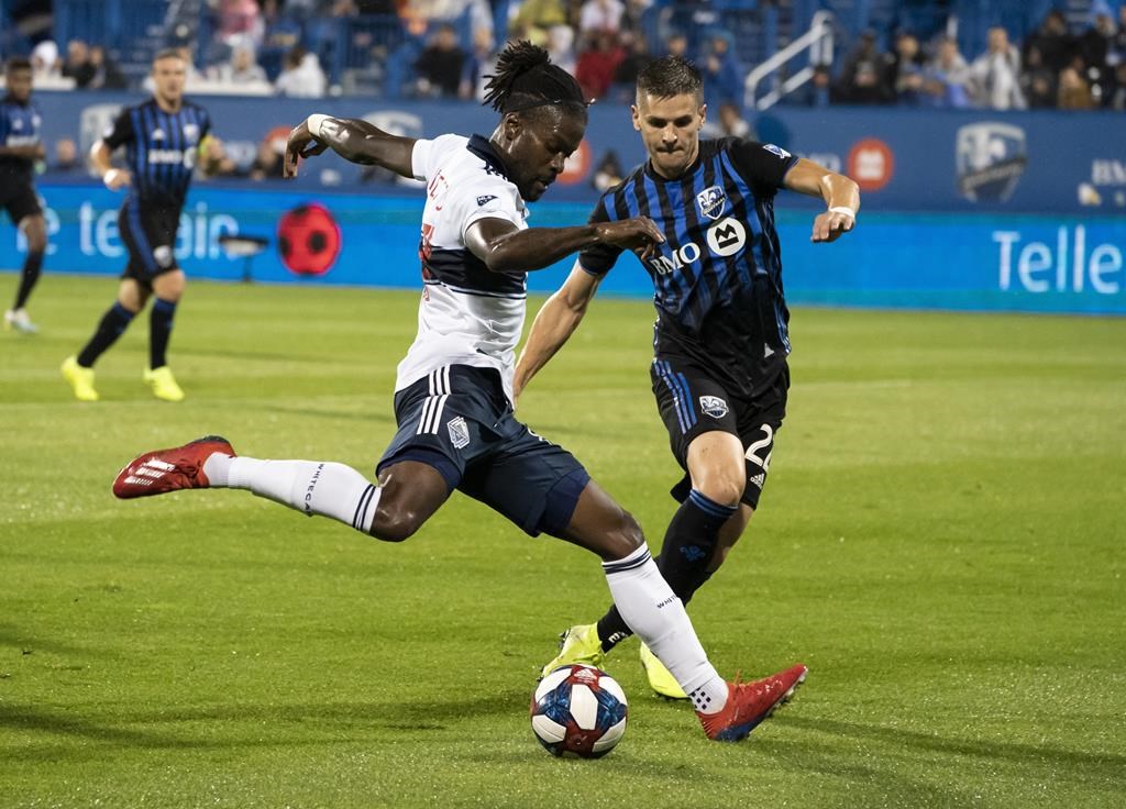 Vancouver Whitecaps forward Yordi Reyna kicks the ball away from Montreal Impact defender Jukka Raitala during first half MLS action in Montreal on Wednesday,.