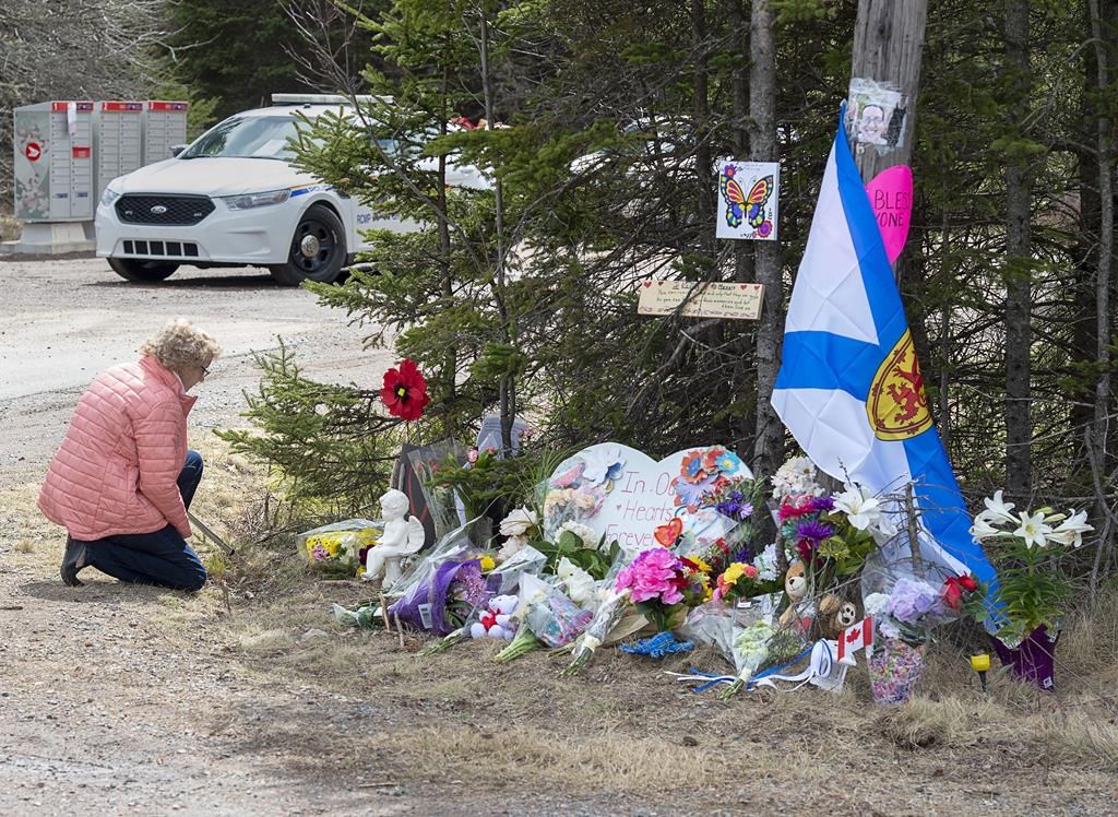 A woman pays her repects at a roadblock in Portapique, N.S., on Wednesday, April 22, 2020.