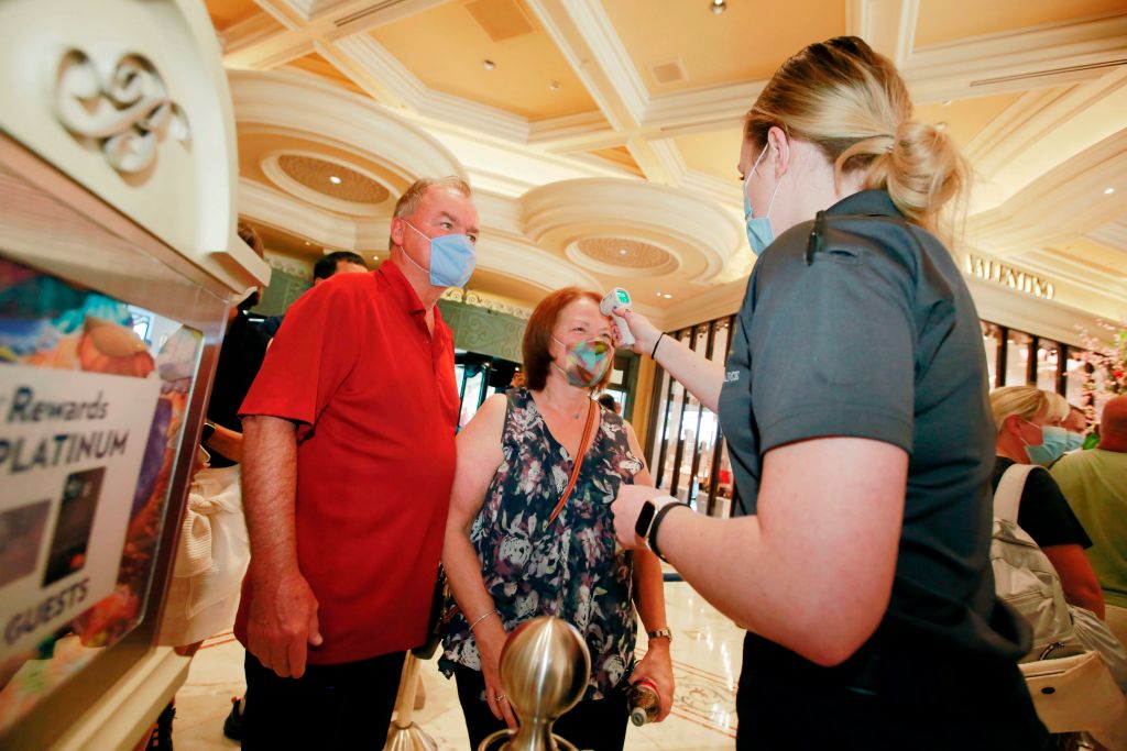 Sue McAvoy, accompanied by her husband Jay, has her temperature taken by Emyli Augustine at the reopening of Bellagio hotel-casino on June 4, 2020, in Las Vegas.