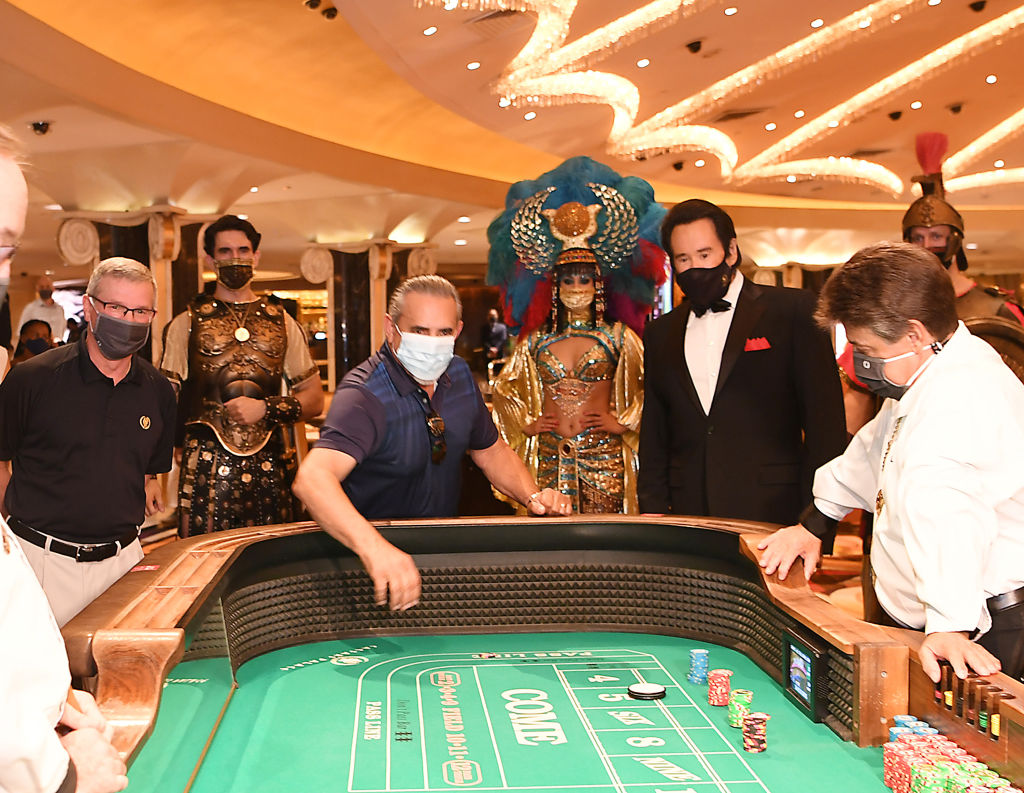 Chief Executive Officer of Caesars Entertainment Tony Rodio (L) and Wayne Newton (2nd R) watch today’s first casino customer Ben Laparne roll the dice at the reopening of Caesars Palace on June 4, n Las Vegas, Nevada.