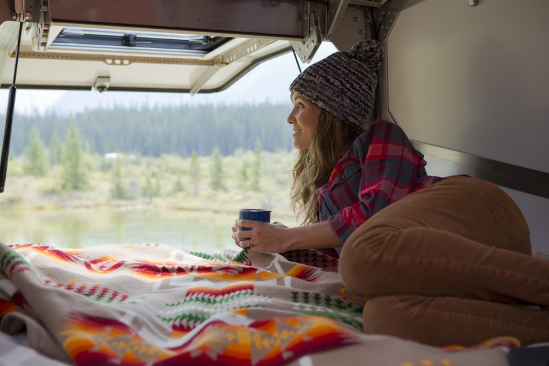 A woman relaxing in a trailer while camping in Jasper National Park.