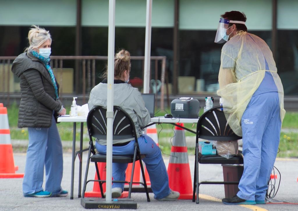Health-care workers wait for people to tested at a COVID-19 mobile testing clinic in Montreal, Sunday, May 31, 2020, as the COVID-19 pandemic continues in Canada and around the world. THE CANADIAN PRESS/Graham Hughes.