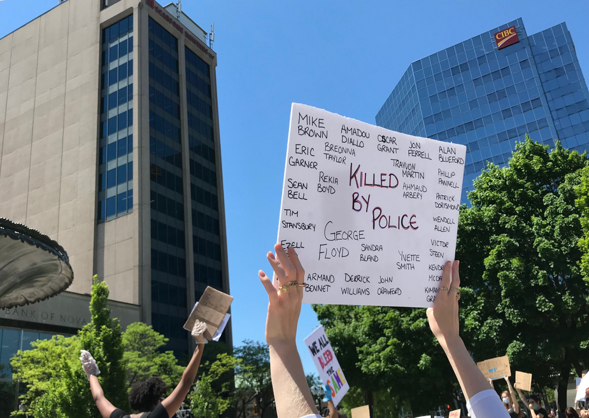 A protester at Monday's rally in downtown Hamilton holds up a sign with the names of black people who have died as a result of police violence.