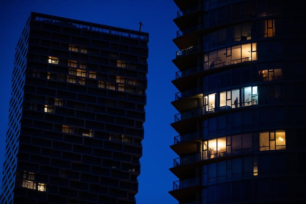 A man stands in the window of an upper floor condo in Vancouver on March 24, 2020. 