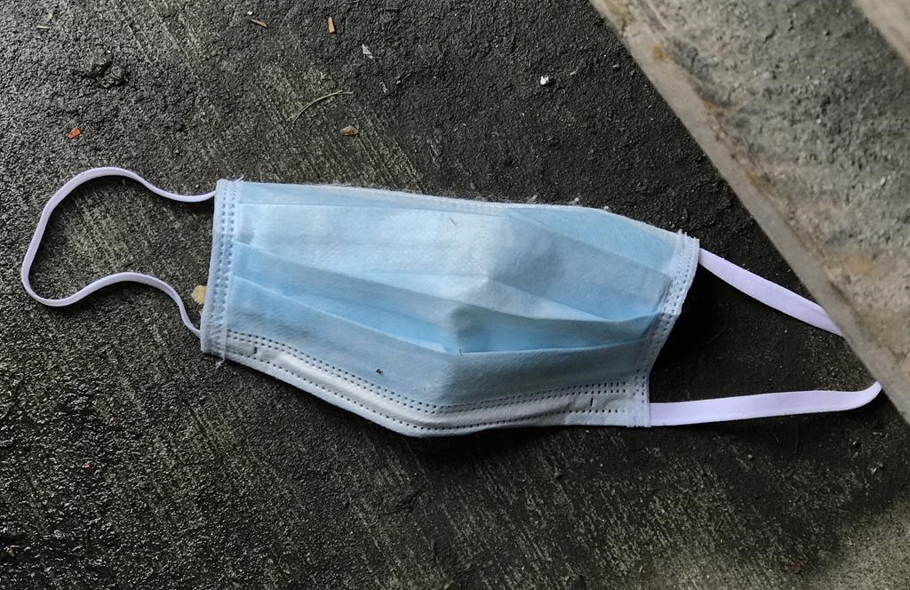 A used protective face mask is seen discarded on the ground in Vancouver, B.C. in May 2020. 