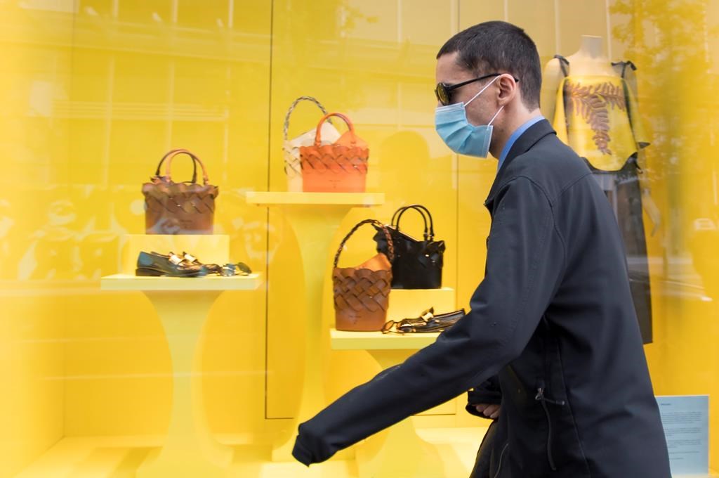 A pedestrian wears a protective face mask as they walk past a re-opened shop in downtown Vancouver, Tuesday, June 2, 2020. Various businesses and restaurants are opening in the province as a part of the phase 2 reopening plan during the COVID-19 pandemic. THE CANADIAN PRESS/Jonathan Hayward.