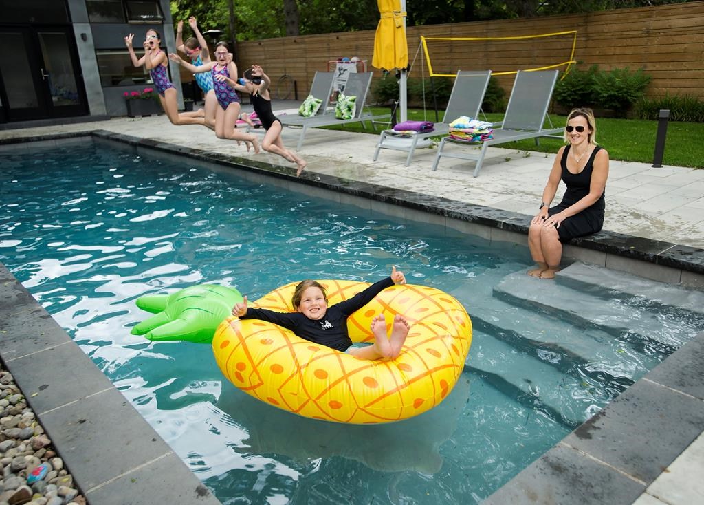 Tory Crowder, right, and her seven-year-old son Stanley, along with his sisters and friends, swim in their swimming pool at their home during the COVID-19 pandemic in Toronto on Wednesday, June 24, 2020. THE CANADIAN PRESS/Nathan Denette.