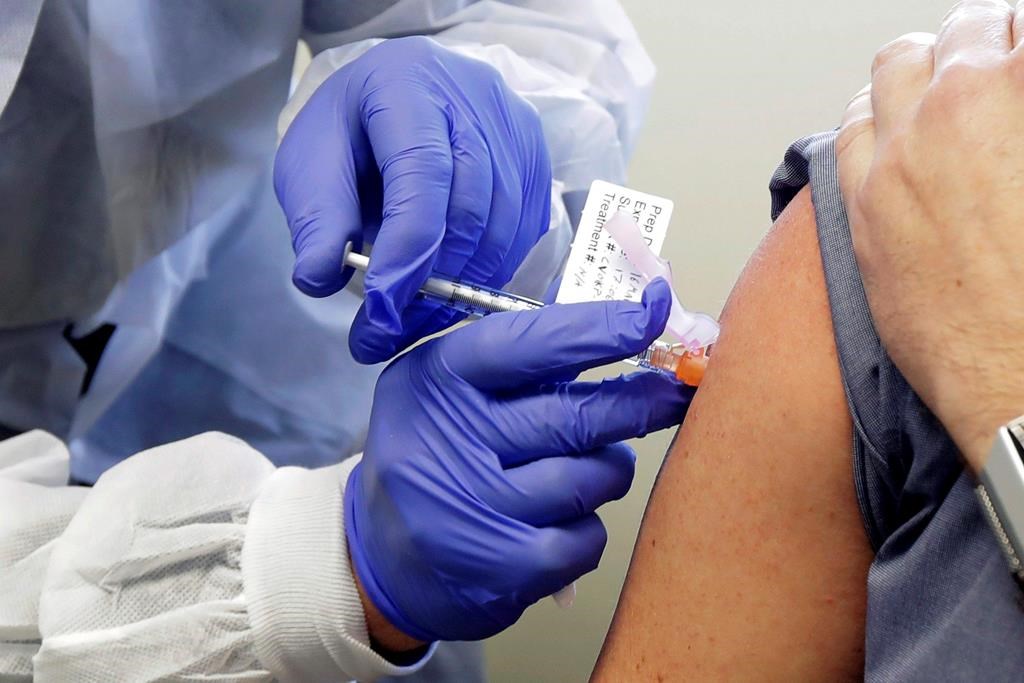 In this March 16, 2020, photo, Neal Browning receives a shot in the first-stage safety study clinical trial of a potential vaccine for COVID-19, at the Kaiser Permanente Washington Health Research Institute in Seattle.