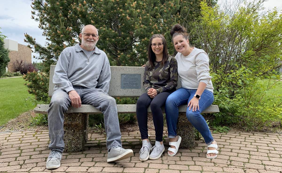 Vernon Barford Junior High School teacher Randy Smith sits with his daughters on a bench dedicated to his late wife.