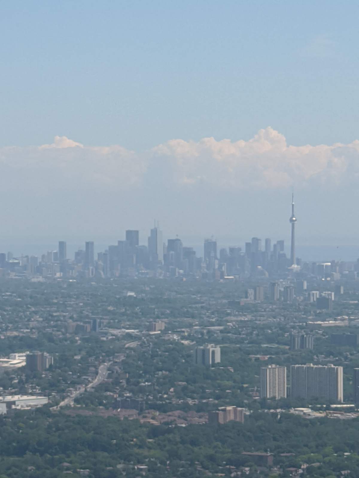 A view of Toronto, including the CN Tower, from the window of an airplane.