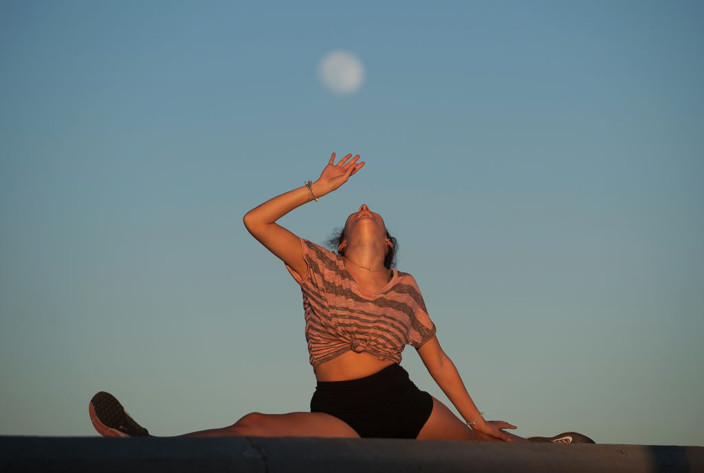 The Strawberry Moon is practically full over the horizon as a lady poses for a photo in Malaga, Spain, on June 4, 2020.