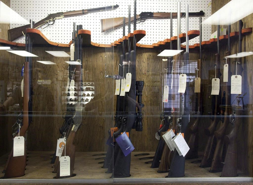 Hunting rifles are seen on display in a glass case at a gun and rifle store.