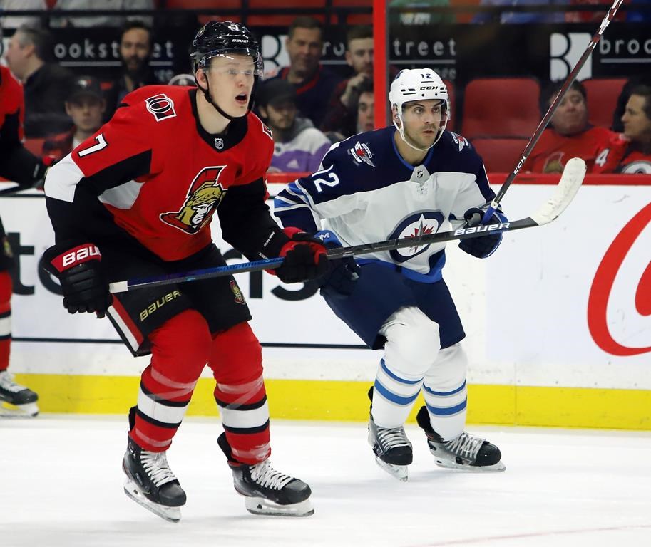 Winnipeg Jets defenceman Dylan DeMelo (12) and Ottawa Senators left-winger Brady Tkachuk (7) look down ice towards the play during second-period NHL action in Ottawa on Thursday, Feb. 20, 2020.