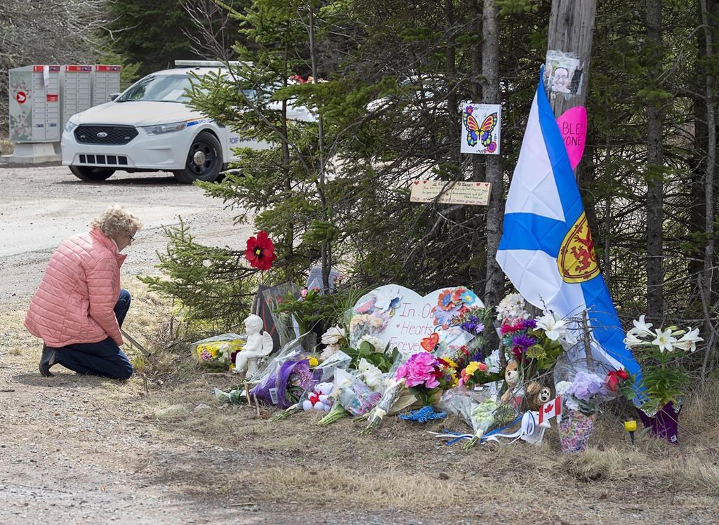 A woman pays her respects to victims of a mass shooting at a roadblock in Portapique, N.S., on Wednesday, April 22, 2020. More than seven weeks after a man disguised as a Mountie killed 22 people in rural Nova Scotia, the RCMP have finally hinted at what may have motivated one of the worst mass killings in Canadian history. THE CANADIAN PRESS/Andrew Vaughan.