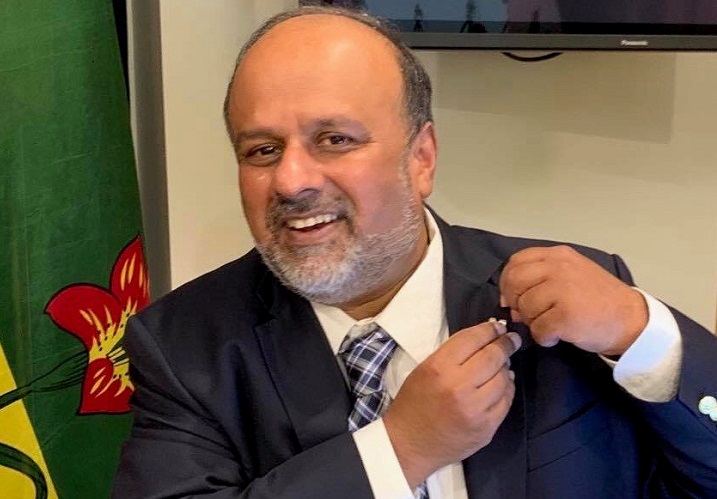Saskatchewan's chief medical health officer Dr. Saqib Shahab puts on the silver knitted-vest pin that was gifted to him by Regina jeweler Megan Hazel.