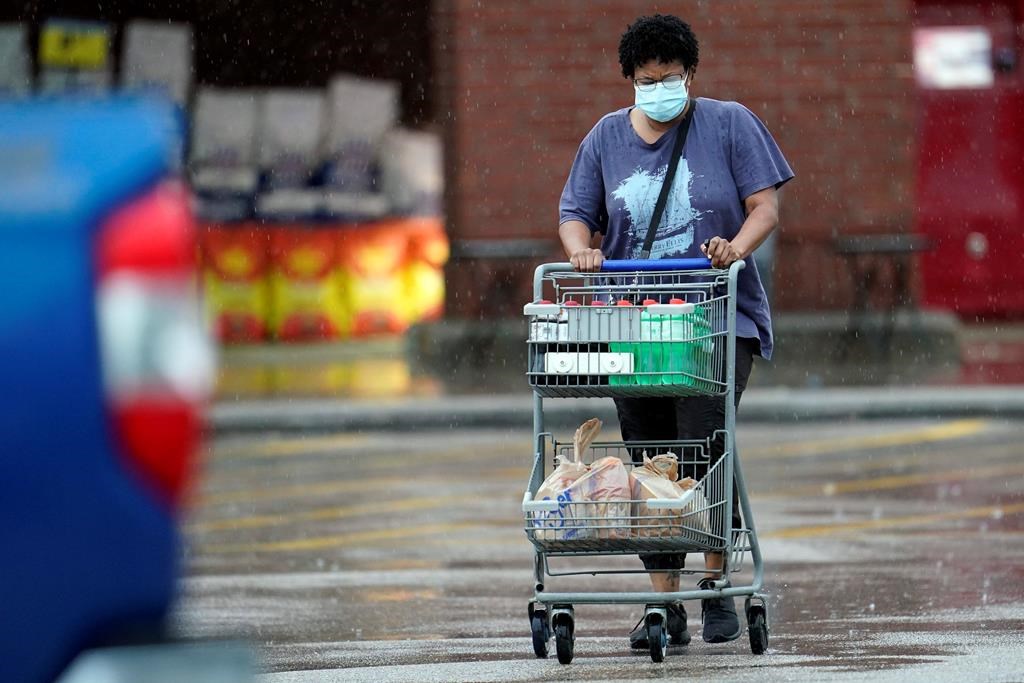 A shopper wears a mask as she pushes her grocery cart in the rain Thursday, June 25, 2020, in Houston, Texas. (AP Photo/David J. Phillip).
