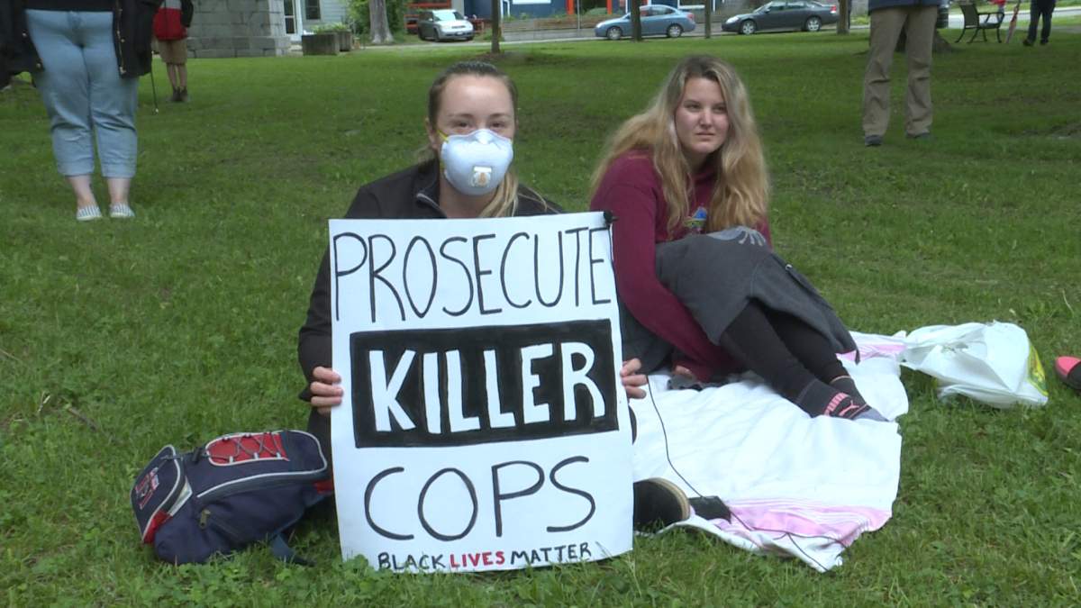 Kayla Oaks holds a sign, Prosecute Killer Cops. Black Lives Matter