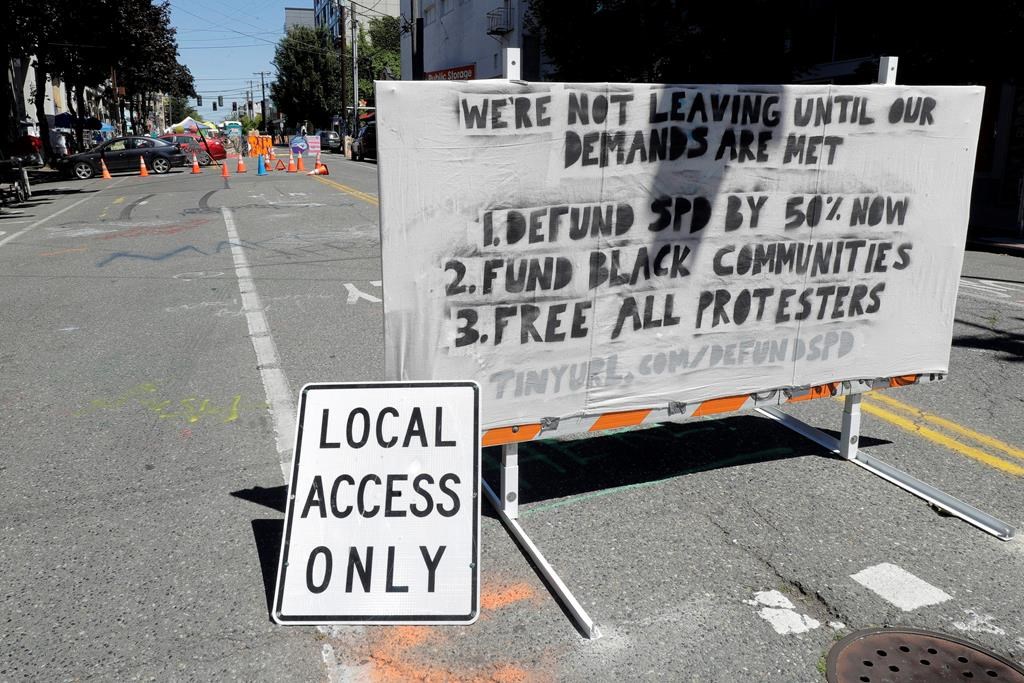 A sign on a street barricade lists some of the demands of protesters in what has been named the Capitol Hill Occupied Protest zone in Seattle, Monday, June 22, 2020. For the second time in less than 48 hours, there was a shooting near the \”CHOP\” area that has been occupied by protesters after Seattle Police pulled back from several blocks of the city\’s Capitol Hill neighborhood near the Police Department\’s East Precinct building.