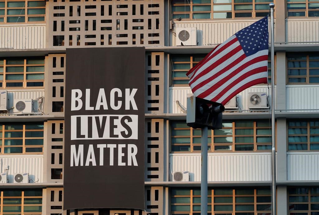 In this June 14, 2020 photo, U.S. flag flutters next to a giant Black Lives Matter banner at the U.S. Embassy in Seoul, South Korea. The banner has been removed from the U.S. Embassy building in South Korea's capital three days after it was raised there in solidarity with protesters back home.