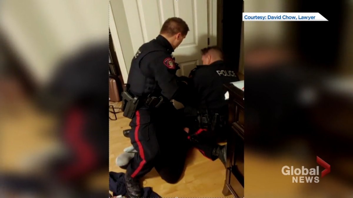 Two Calgary police officers are seen kneeling and leaning on a woman during an arrest in October 2019.