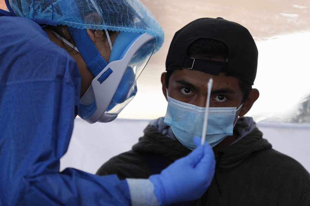 Dr. Diana Pacheco explains to a patient that she will collect nasal and throat swabs, during walk-up COVID-19 testing in a mobile diagnostic tent.