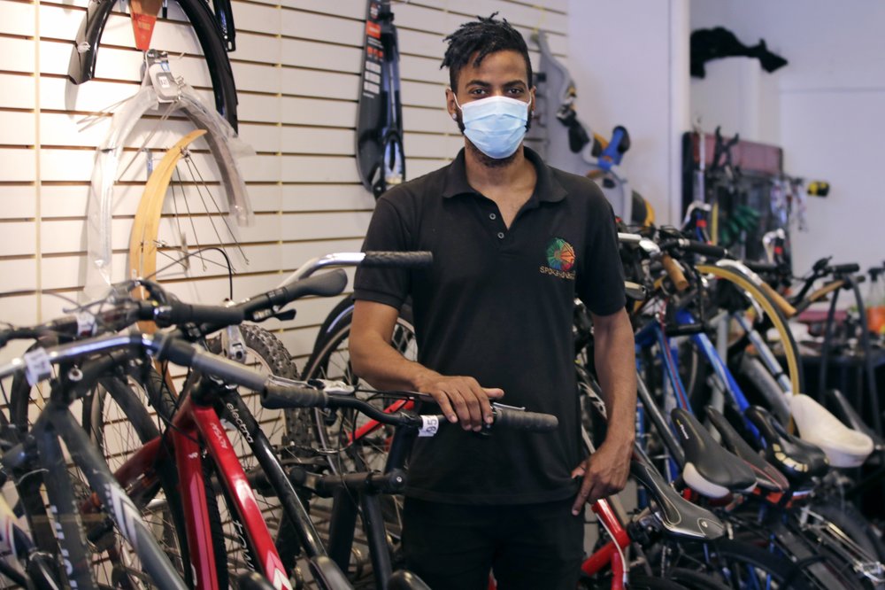 In this Wednesday, June 24, 2020, photograph, Noah Hicks, owner of Spokehouse Bikes in the Upham’s Corner neighborhood of Boston, poses at his shop.