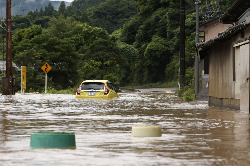 A car is stuck in a flooded road by heavy rain in Yatsushiro, Kumamoto prefecture, southwestern Japan, Saturday, July 4, 2020. The Japan Meteorological Agency raised the heavy rain warnings in many parts of the prefectures to the highest level shortly before 5 a.m. It was the first time for the agency to do so in the two prefectures, Kumamoto and Kagoshima. 