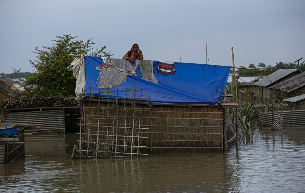 A flood affected Indian woman stands on the roof of her partially submerged house along river Brahmaputra in Morigaon district, Assam, India, Thursday, July 16, 2020. Floods and landslides triggered by heavy monsoon rains have killed dozens of people in this northeastern region. 