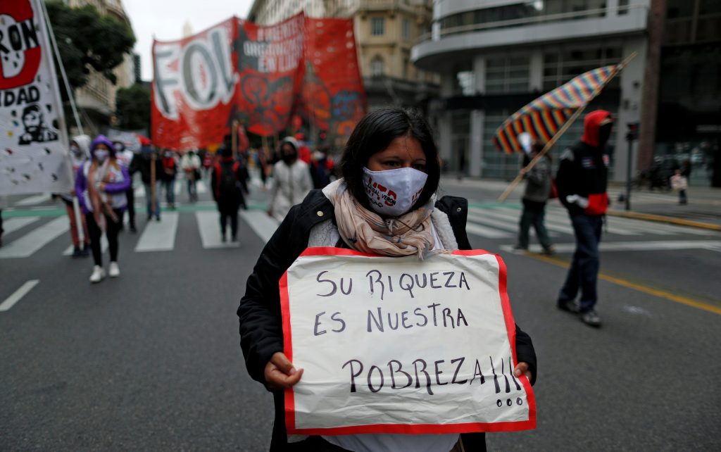FILE PHOTO: A demonstrator holds a placard that reads "their richness is our poverty", during a protest to demand resources for the vulnerable, amid the coronavirus disease (COVID-19) lockdown, in Buenos Aires, Argentina May 21, 2020. 