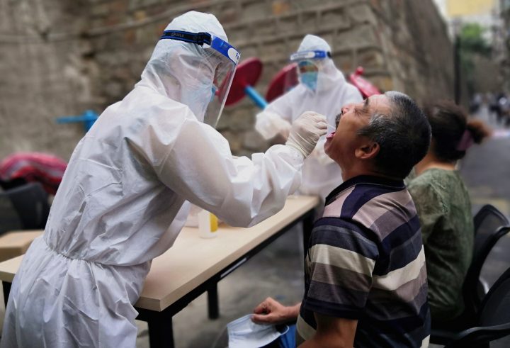 A medical worker in protective suit collects a swab from a man to conduct free nucleic acid tests for residents in the residential compound, after new cases of coronavirus disease (COVID-19) were found in Urumqi, Xinjiang province, China July 19, 2020. Picture taken July 19, 2020. 