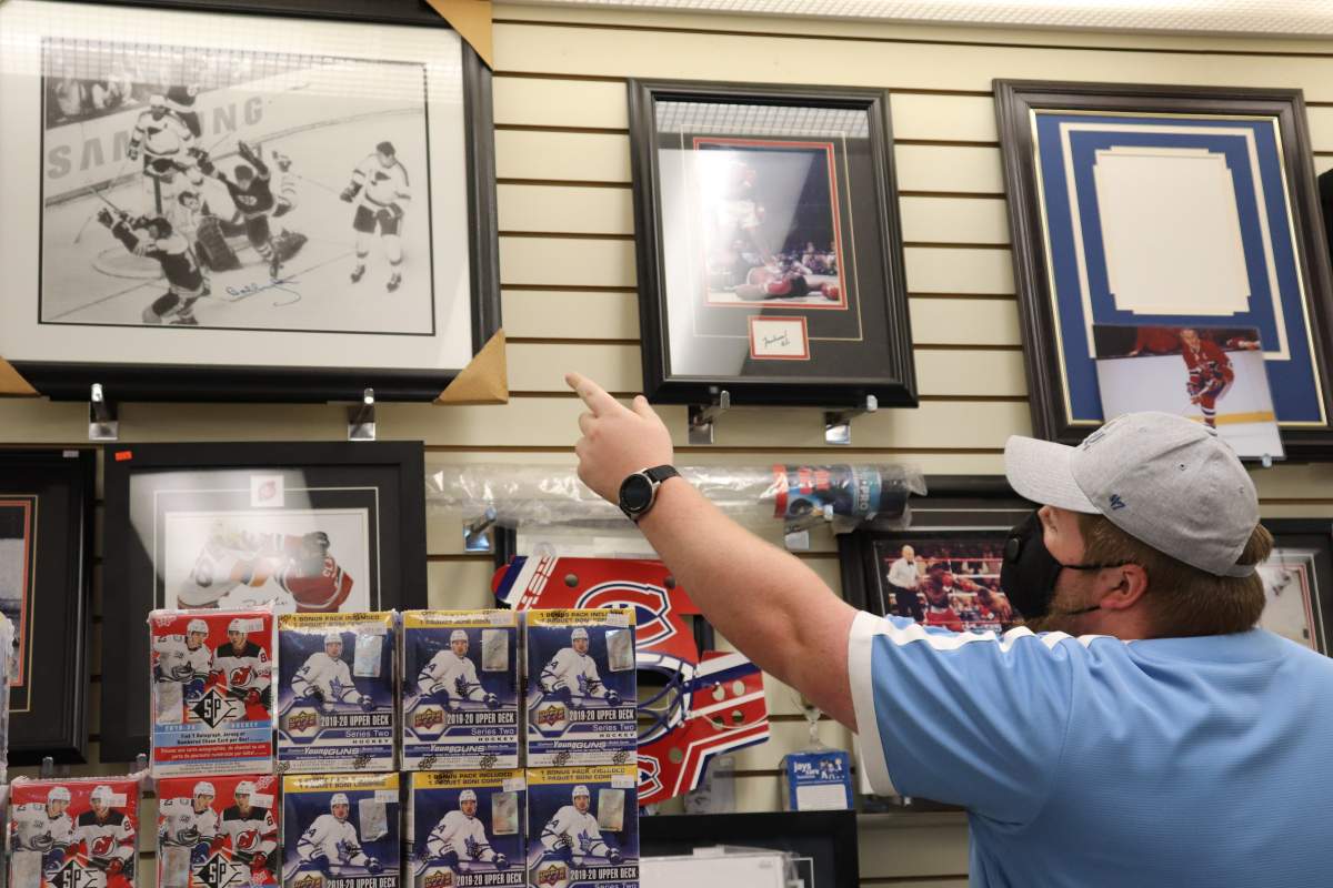 Bluenose Collectible employee, Matthew Trudel, points out Bobby Orr’s autograph framed on the shop’s wall on Tuesday, July 21, 2020.
