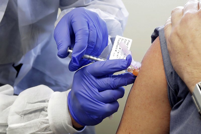 In this March 16, 2020 file photo, a subject receives a shot in the first-stage safety study clinical trial of a vaccine by Moderna for COVID-19, the disease caused by the new coronavirus, at the Kaiser Permanente Washington Health Research Institute in Seattle.