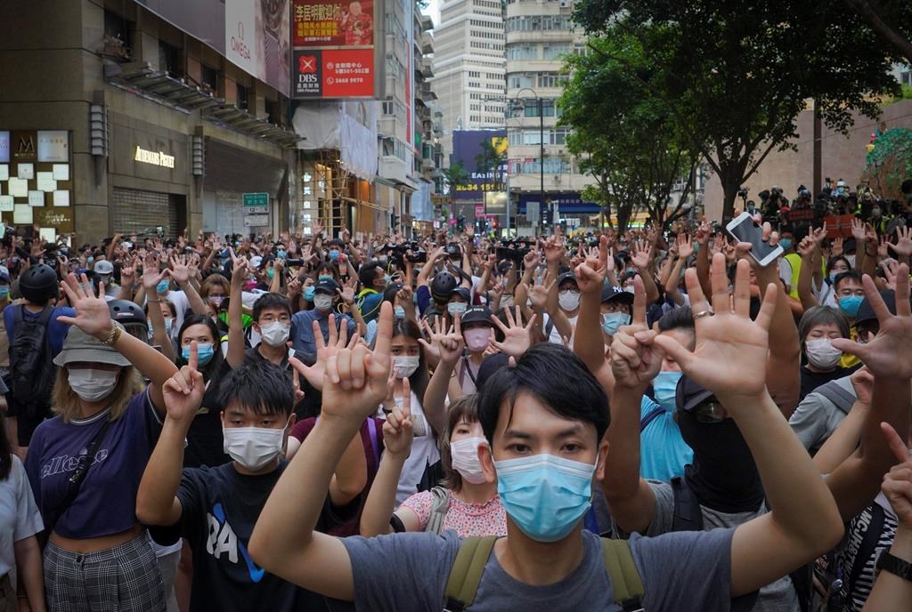 In this July 1, 2020, file photo, protesters against the new national security law gesture with five fingers, signifying the ‘Five demands — not one less’ on the anniversary of Hong Kong’s handover to China from Britain in Hong Kong. (AP Photo/Vincent Yu, file)