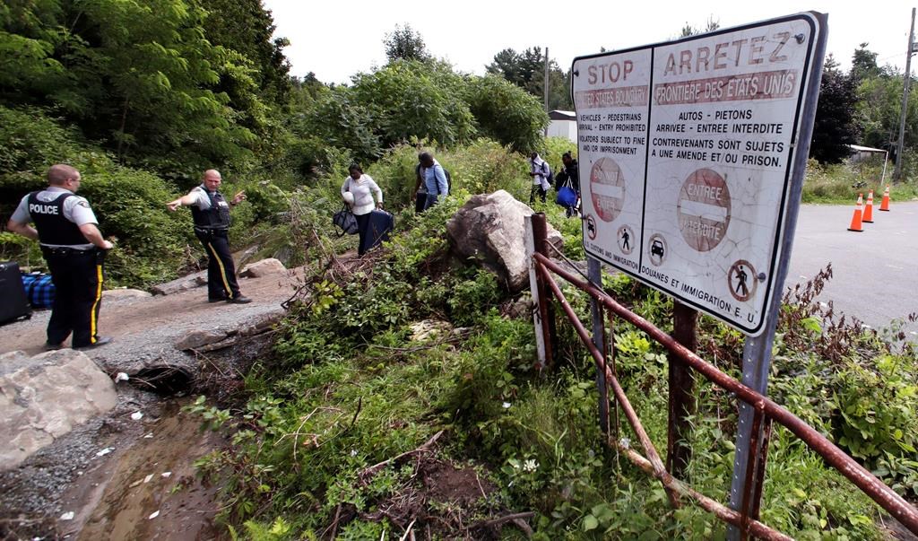 Royal Canadian Mounted Police officers greet migrants as they enter into Canada at an unofficial border crossing at the end of Roxham Road in Champlain, N.Y. Aug. 7, 2017.
