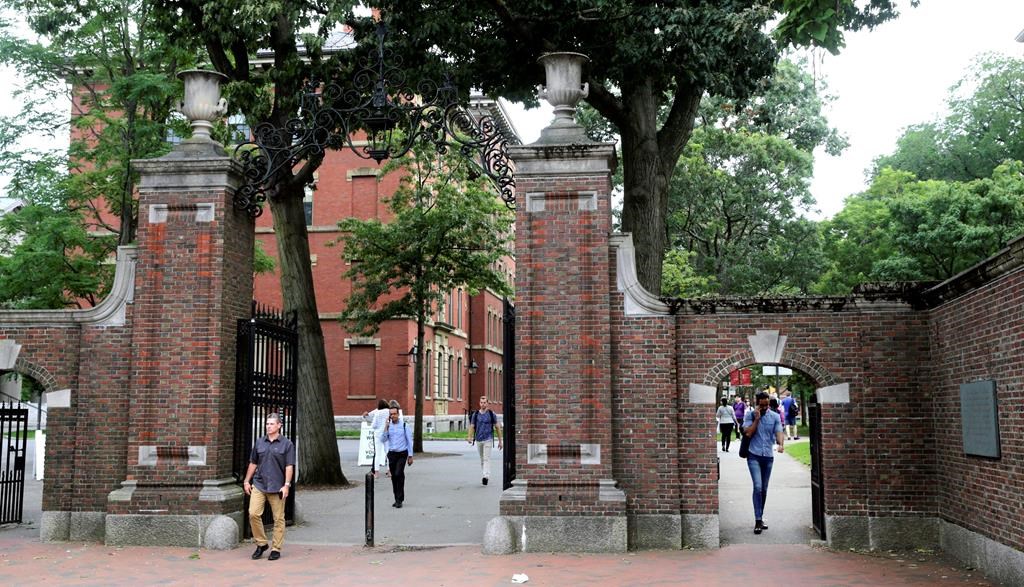 FILE - In this Aug. 13, 2019, file photo, pedestrians walk through the gates of Harvard Yard at Harvard University in Cambridge, Mass.
